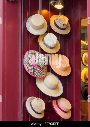 Elegant Straw Hats Displayed on a Red Door in a Fashionable Boutique Stock Photo
