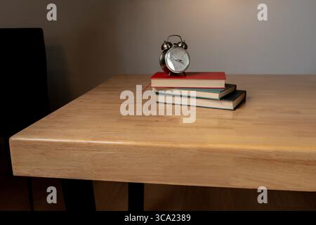 Classic alarm clock resting on books with ambient warm lighting in a peaceful indoor setting. Stock Photo