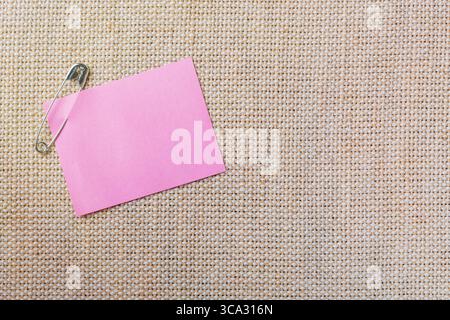 Pink sticker note with pin on canvas background. Stock Photo