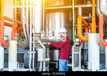Young man mechanical engineer is checking and inspection of HVAC heating ventilation air conditioning system and pipping line of industrial constructi Stock Photo