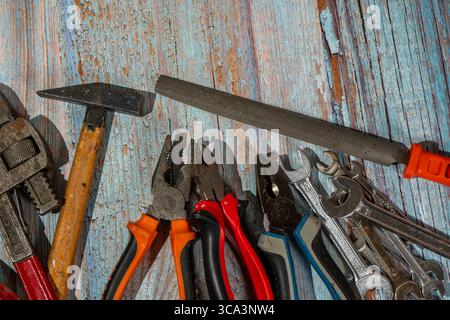 Hammer, pliers, wrenches, and file lying on a wooden workbench, ready to be used for house maintenance Stock Photo
