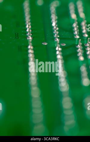 circuit board with contacts, a simple green printed circuit board with an electronic circuit with soldered elements Stock Photo