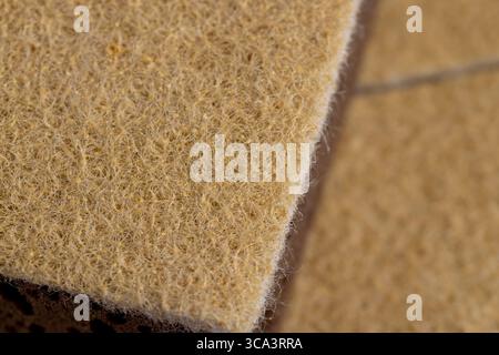 glued and tightly intertwined synthetic sand-colored threads on a sponge that is used for cleaning and washing, closeup Stock Photo