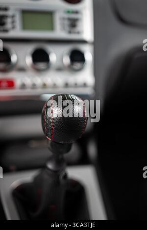 Six speed, black leather wrapped gear knob of a manual or stick shift gearbox in a car. Close up detail shot, shallow depth of field, no people Stock Photo