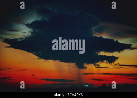 Dark thundercloud cell and rain at sunset Stock Photo