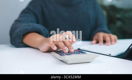 Person working on financial tasks with calculator and digital tablet, symbolizing accounting, budget management, tax preparation, and personal or smal Stock Photo