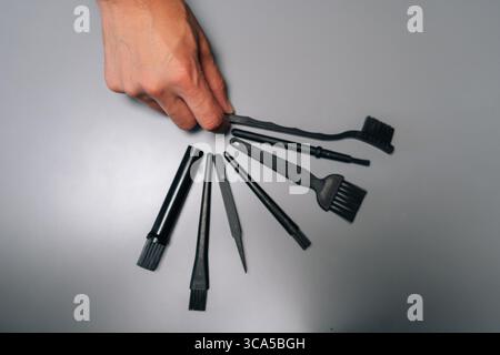 Top view of technician holding set of specialized cleaning tools, including brushes, tweezers, blower, designed for meticulous computer maintenance Stock Photo