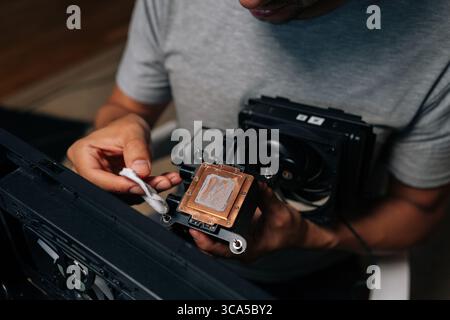 Close-up top view of precise computer maintenance involving cleaning processor cooling system, wiping electronic components with white microfiber Stock Photo
