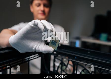 Computer technician wearing white gloves showing CPU during installation into motherboard socket of desktop computer, upgrading processing power. Stock Photo