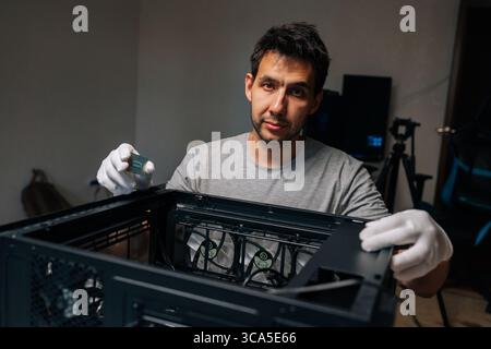 Computer technician wearing white gloves installing CPU into desktop computer motherboard, upgrading or repairing hardware components at home, looking Stock Photo