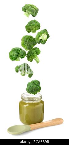 Baby food. Broccoli falling into jar of puree on white background Stock Photo