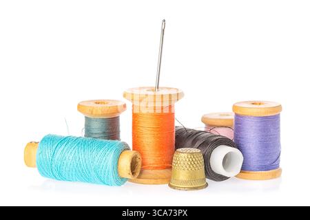 Collection of color thread spools with needle and thimble isolated on white background. Sewing concept Stock Photo