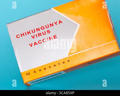 Close-up of a box labeled "CHIKUNGUNYA VIRUS VACCINE" in bold red text on orange and white packaging. The box contains 12 capsules and is placed again Stock Photo