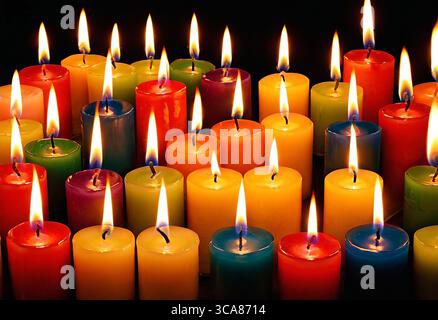 Close-up of multicolored burning candles in the dark, bright colorful background Stock Photo