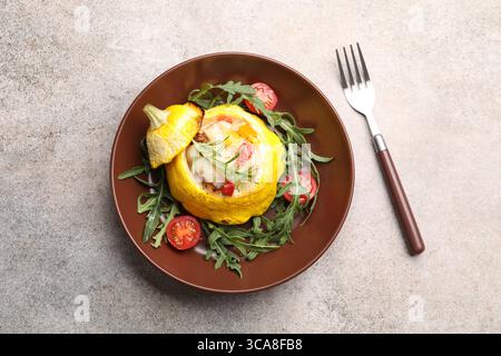 Tasty stuffed pattypan squash with tomatoes and arugula served on grey table, top view Stock Photo
