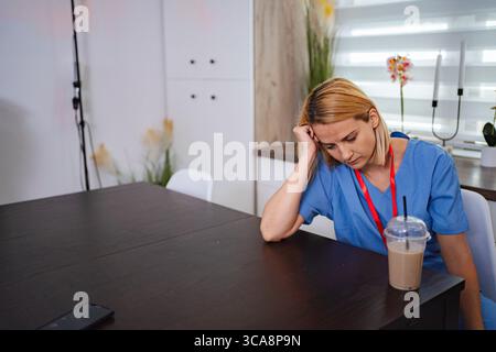 Exhausted nurse resting her head on a table during a break Stock Photo
