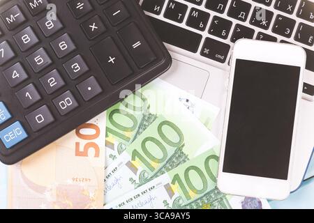 Business concept. Working desk with laptop, calculator, clock, phone and euro bank notes money. Close up image. Stock Photo