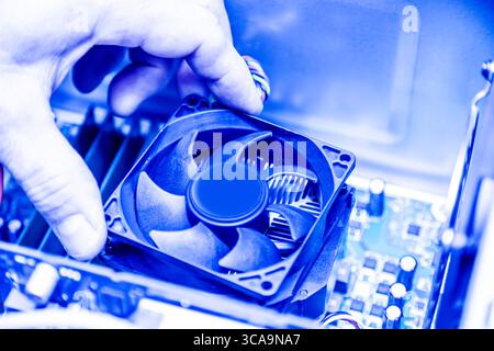 Technician hands installing CPU cooler fan on a computer pc motherboard. Toned image. Stock Photo