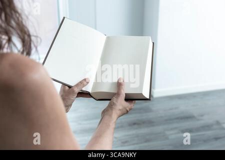 Woman displaying an open book with blank pages, offering copy space for text or design in a contemporary setting Stock Photo