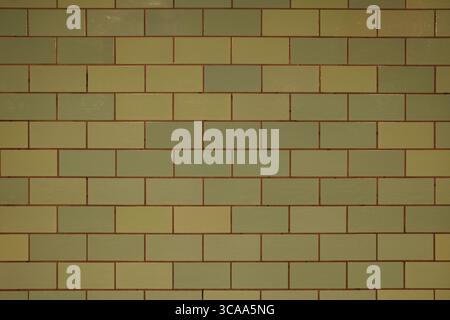 A flat, head-on view of a vintage or retro tiled wall. The rectangular ceramic tiles, in varying shades of muted green, are arranged in a classic. Stock Photo