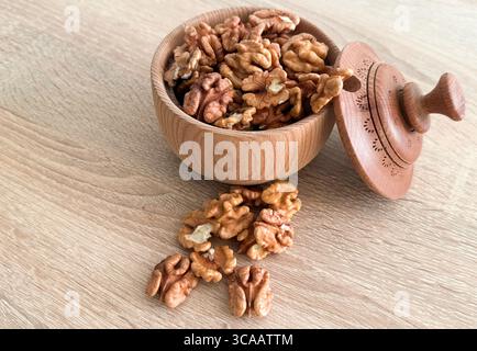 Walnuts kernels on dark desk with color background, Whole walnut in wood vintage bowl. Stock Photo