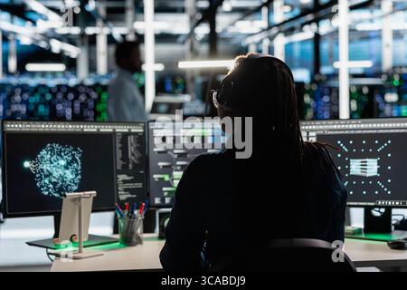 Data center admin uses AI visualization tool on PC to optimize resource allocation. Server farm employee uses artificial intelligence analysis software on computer to do maintenance Stock Photo