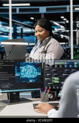 Server room system administrator using artificial intelligence to reduce downtime. African american employee designs and implements AI driven solutions for data center equipment Stock Photo