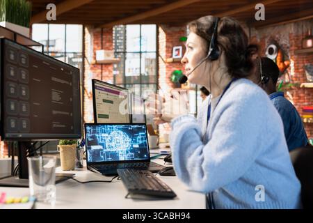 Call center employee in office using AI chatbot to provide quick replies to common customer queries. Woman doing customer service job generating automated responses to clients using AI Stock Photo