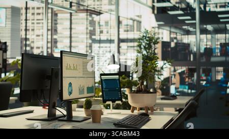 Tablet and PC on desk displaying financial graphs of company profits performance metrics. Data analytics on device display showing corporate business earnings KPIs. panning shot Stock Photo