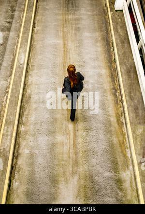 An overhead shot of a woman in a black suit running down a concrete path. Stock Photo