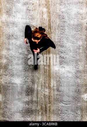 A woman in black clothing is walking on a surface that appears to be a waterfall. Stock Photo