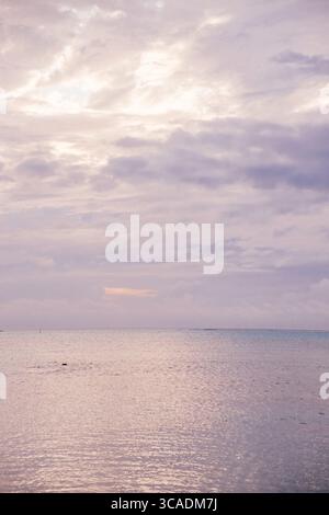 Pastel sunset over calm ocean waters on Moorea Island, French Polynesia. Stock Photo