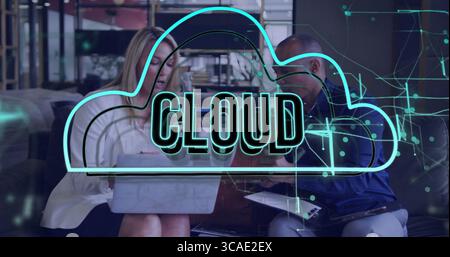 Collaborating colleagues sitting on couch using laptop, tablet in office lounge, with cloud graphic Stock Photo