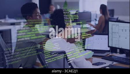 Collaborating two women developers reviewing code on office monitors, with keyboard mouse laptop Stock Photo