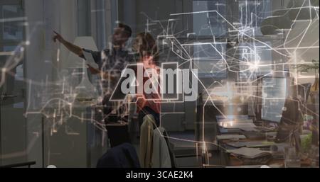 Pointing tech team analyzing network diagrams in modern office, with laptops and printed report Stock Photo