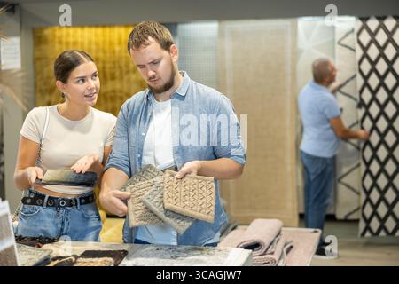 Husband and wife look at samples of carpet fabrics, small pieces of floor pile coverings. Stock Photo
