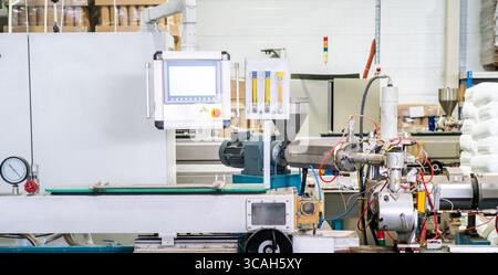 Plastic extrusion machine with control panel in smart factory. Polymer processing, automation technology and industrial production. Stock Photo