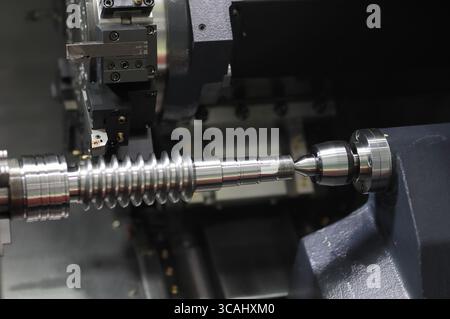 Worm shaft cutting process on CNC turret lathe machine close up. Selective focus. Stock Photo
