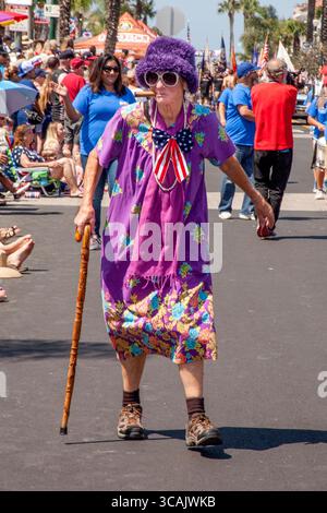 July 4, 2017, Huntington Beach, California: A costumed cigar-chomping ''Aunt Gertie'' in a purple dress is portrayed by a 1963 graduate of Huntington Beach High School as she marches in a July 4th parade in Huntington Beach, CA. (Credit Image: © Spencer Grant/ZUMA Press Wire) Stock Photo