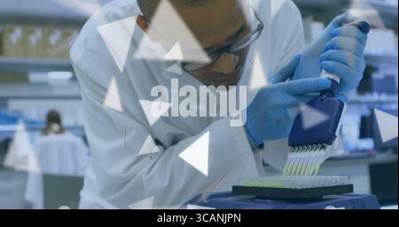 Dispensing technician wearing safety glasses, lab coat using pipette into microplate at lab bench Stock Photo