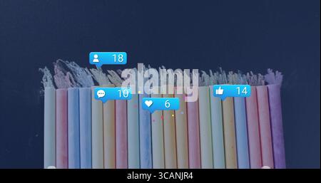 Displaying pastel chalk sticks lining up on slate surface, showing floating notification icons Stock Photo