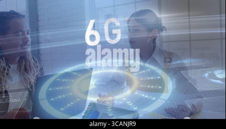 Collaborating professionals inputting on laptop and tablet in office with holographic 6G overlay Stock Photo