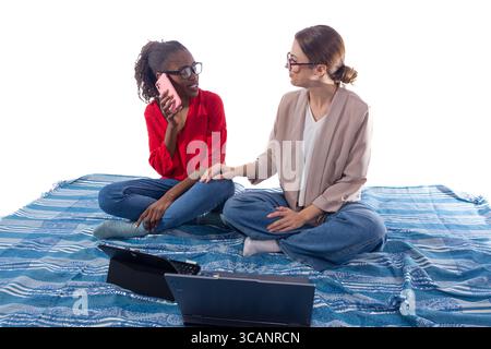 Two women working remotely using laptop and mobile phone Stock Photo