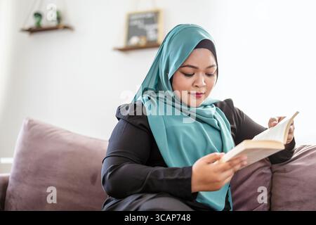 Muslim woman reading the Koran at home Stock Photo