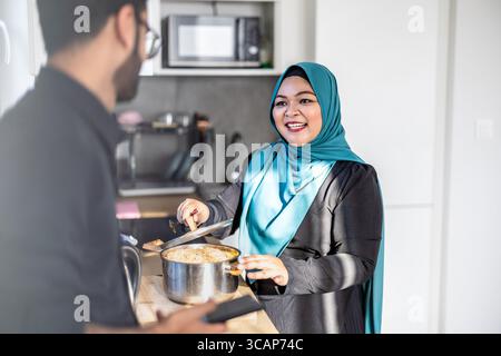 Portrait of a happy Muslim couple standing in the kitchen Stock Photo