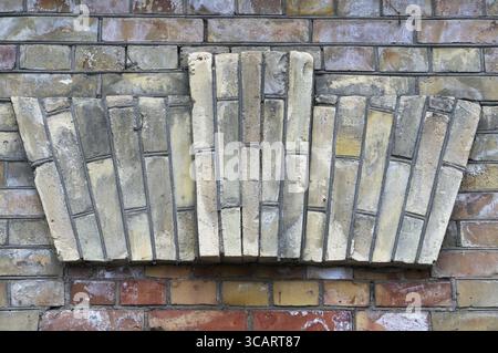 Decorative element in the form of a crown made from yellow bricks on an old aged wall Stock Photo