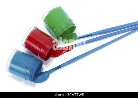 Open plastic cans of red blue green leaked paint and arts brushes macro Stock Photo