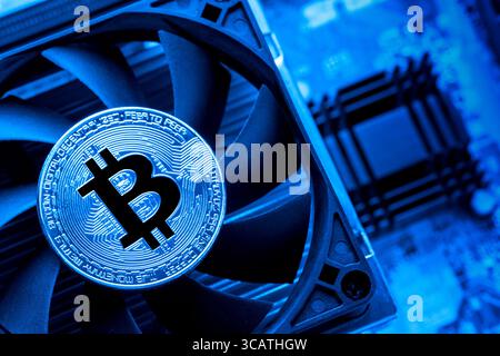 Bitcoin on the CPU processor cooper and computer circuit motherboard close up. Cryptocurrency virtual money background. Blue toned. Stock Photo