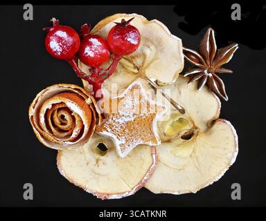 Christmas homemade decoration objects made of dry red orange peels, cones, berries and apples. Isolated on black night macro Stock Photo
