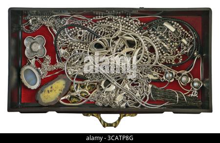 A young woman keeps her silver and gold rings chains and bracelets in a dusty mass production of dark red plastic box . Isolated on white top view Stock Photo